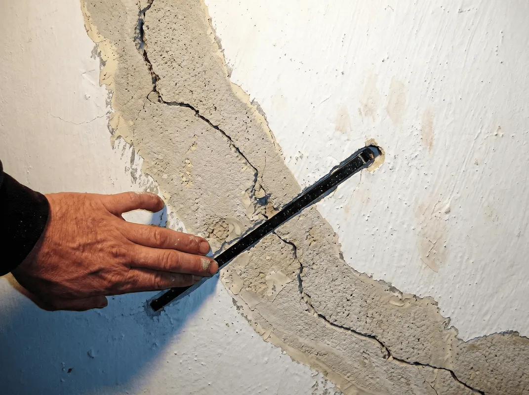 A wall with a large crack is being inspected by a professional in Cincinnati, OH